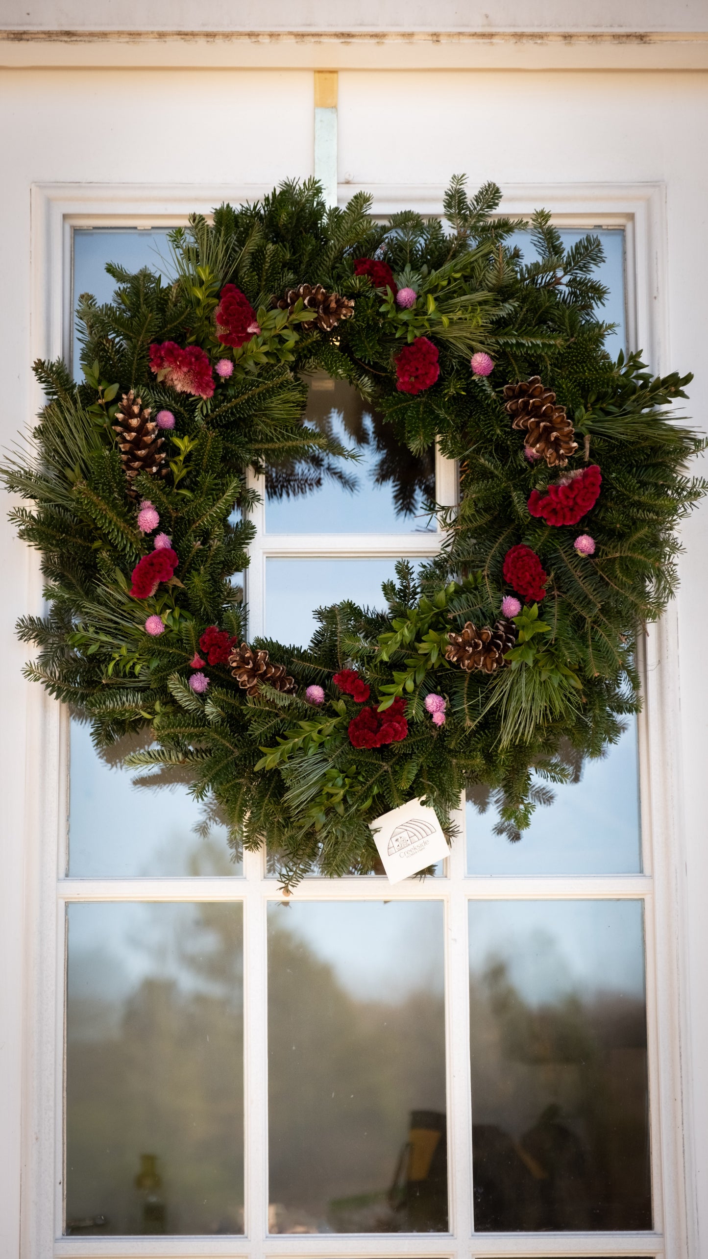 Christmas wreath with red berries and pine cones on a door