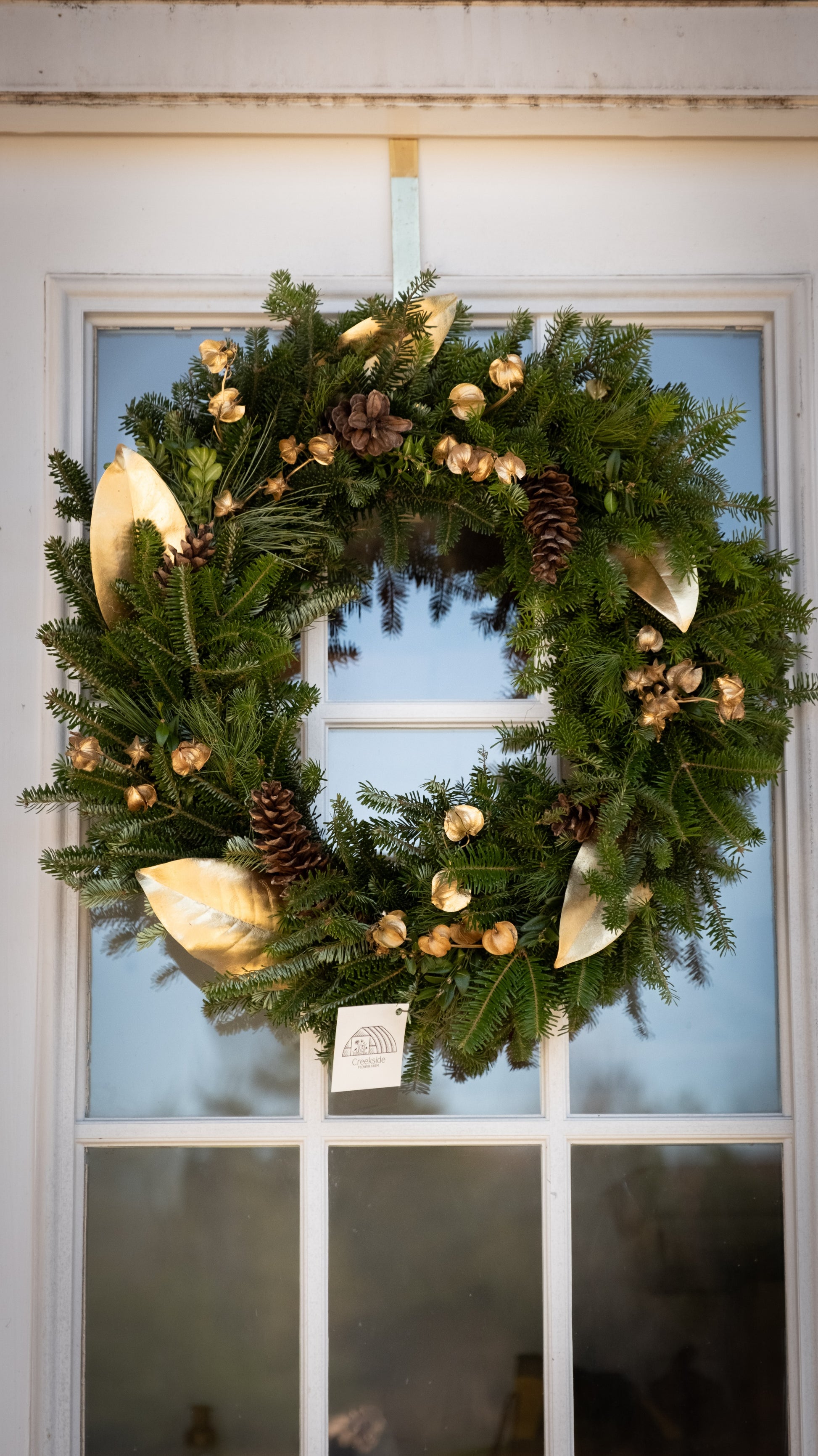 Christmas wreath with gold accents and pinecones on a door